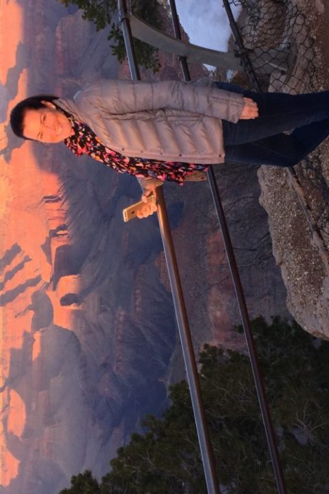 A visitor posing for a picture as the sun sets in the background at Private Sunset Tour