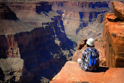 The North Rim of Grand Canyon National Park with a hiker sitting and enjoying the view