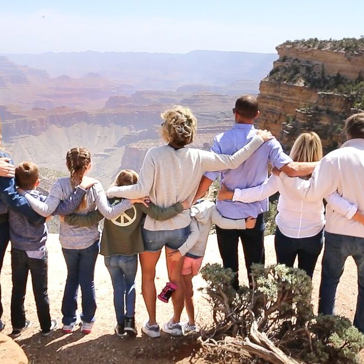 A tour group posing arm-in-arm for picture while overlooking the Grand Canyon