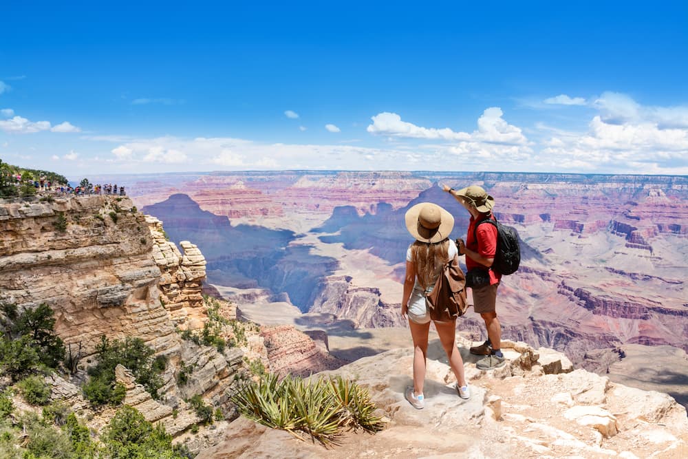 A couple overlook the Grand Canyon from a ridge in the summer