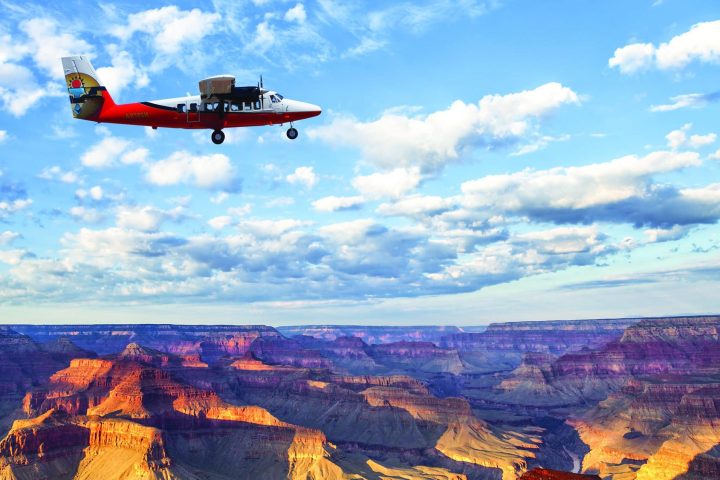 a plane flying in the air with a mountain in the background