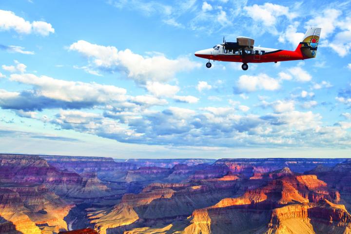 a plane flying in the air with a mountain in the background
