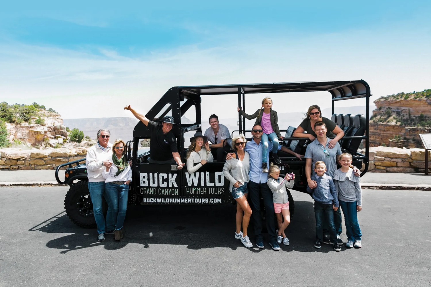 People posing with an off-road tour vehicle at a scenic overlook.