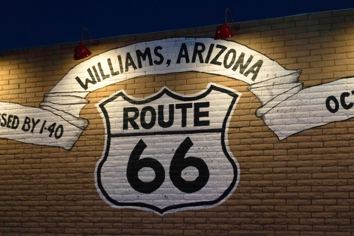 Route 66 mural in Williams, Arizona on a brick wall at night.